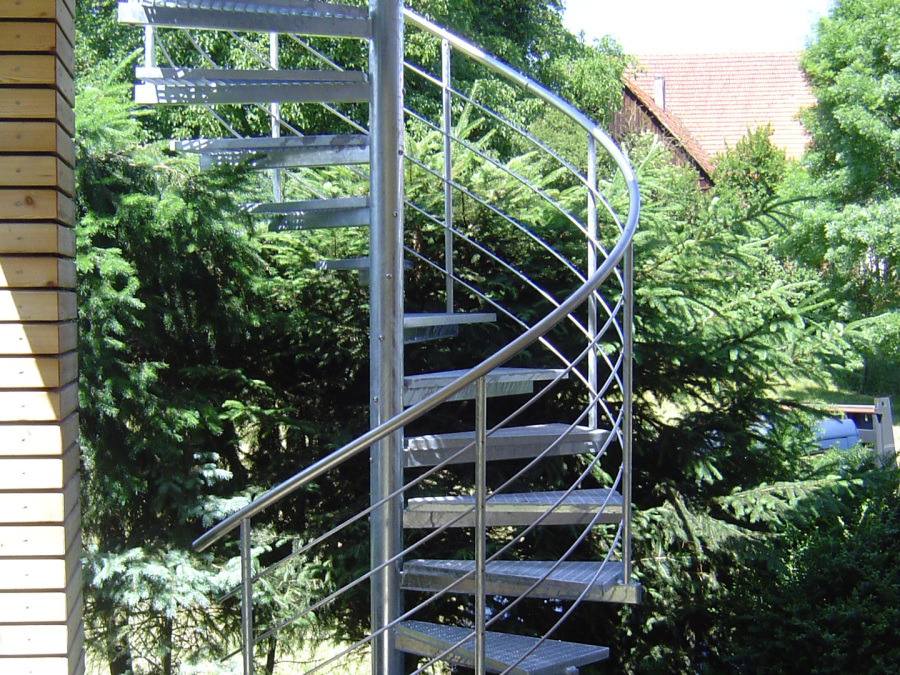 Spindeltreppe aus Metall mit geschwungenem Handlauf im Außenbereich.